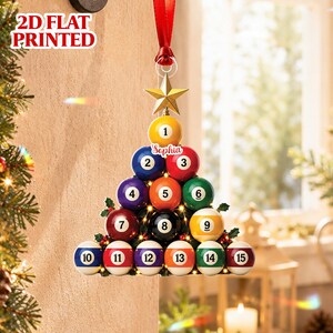 May include: A 2D flat printed Christmas tree ornament shaped like a pyramid of billiard balls numbered 1 through 15. The ornament features a gold star at the top, a red ribbon for hanging, and the name Sophia printed on the number 2 ball.