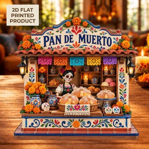 May include: A 2D flat printed decorative display featuring a bakery stall labeled PAN DE MUERTO. The scene includes a figure with skull face paint, shelves with miniature pottery, baskets of bread, marigold flowers, and hanging papel picado.