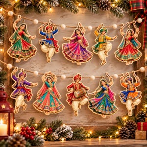 May include: A decorative garland featuring ten wooden cutouts of figures in traditional Indian dance attire, including vibrant lehengas and kurtas, suspended on a string with white pom-poms, arranged in two rows against a rustic wooden background.
