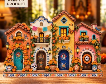 May include: A 2D flat printed product featuring a row of four colorful miniature buildings with orange marigold flowers, skull decorations, balconies, and arched doors. The scene includes vibrant pink, yellow, and blue facades with intricate floral patterns.