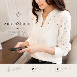 Könnte beinhalten: Eine weiße Langarmbluse mit einem komplizierten Lochstickereimuster, einem V-Ausschnitt und gerippten Bündchen. Das Bild enthält den Text ZarelaStudio, Timeless style, made for you, Timeless design, Premium quality und Made for you.