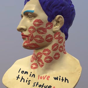Puede incluir: Escultura de busto con pelo azul, cejas azules y labios rojos. La cara y el cuello están cubiertos de huellas de labios rojos. La base del busto tiene el texto "I am in love with this statue."