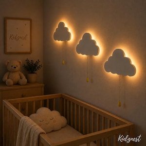 Könnte beinhalten: Eine Szene im Kinderzimmer mit drei wolkenförmigen Wandleuchten, die ein warmes Licht ausstrahlen. Ein Holzbettchen, eine Kommode und ein gerahmtes Kunstwerk mit dem Text "KidzNest" sind zu sehen. Ein Teddybär und ein wolkenförmiges Kissen tragen zur gemütlichen Atmosphäre bei.
