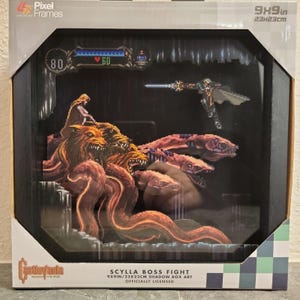 May include: A Pixel Frames shadow box art titled Scylla Boss Fight, measuring 9x9 inches. The display features a multi-layered pixel art scene from Castlevania, showing a character with a sword facing a multi-headed creature in a dark environment.