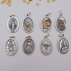 May include: A collection of eight oval-shaped metal religious pendants featuring various figures and symbols. The charms include depictions of the Virgin Mary, the Holy Family, St. Michael, the Divine Mercy, a dove, and a Guardian Angel with text.