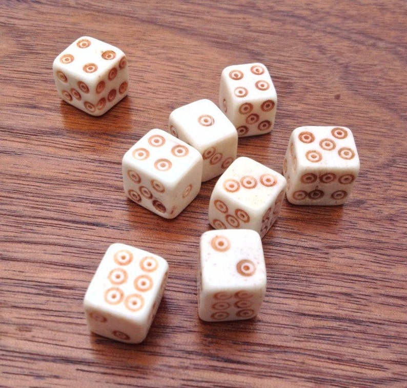 May include: Seven white dice with brown dots on a wooden surface. Each die has a different number of dots.