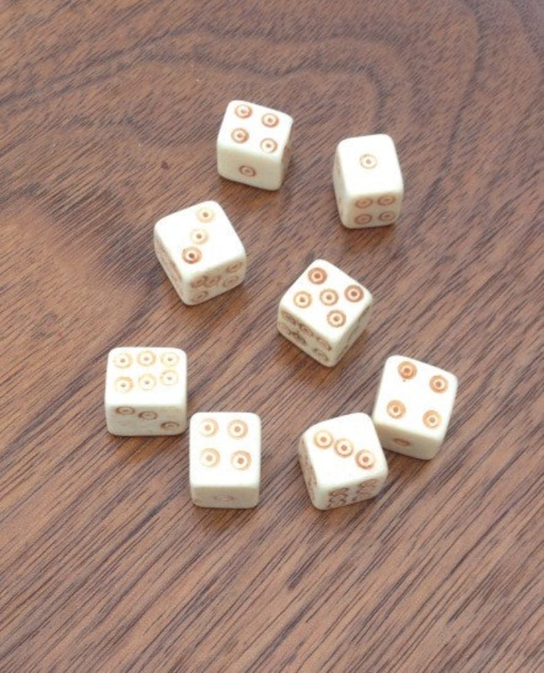 May include: Eight white dice with brown dots on each side. The dice are arranged in a semi-circle on a wooden surface.