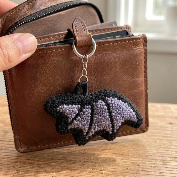 A punch-needle bat-wing keychain is a genuinely niche, tactile craft object you won't find at any chain store — spooky-cute textile art you carry with you.