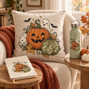 Puede incluir: Un cojín cuadrado, un cuaderno de tapa dura y una botella de agua de metal verde claro, todos con un gráfico a juego de un fantasma sonriente, una calabaza naranja grande, una calabaza blanca, una calabaza verde y murciélagos negros.