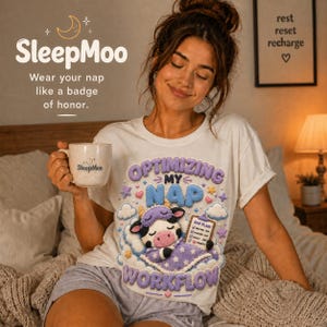 May include: A woman wearing a white t-shirt with a graphic that says "Optimizing My Nap Workflow". The shirt features a cartoon cow wearing a sleep mask. She is holding a mug that says "SleepMoo". The image also includes the text "Wear your nap like a badge of honor."