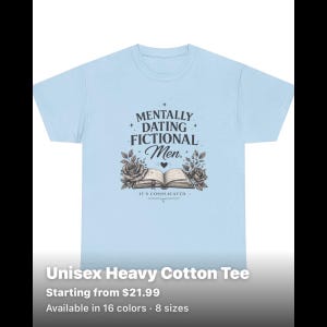 May include: A light blue short-sleeved t-shirt featuring a dark graphic print. The design includes the text "MENTALLY DATING FICTIONAL Men." above an illustration of an open book flanked by two roses, with the text "IT'S COMPLICATED" below the book.