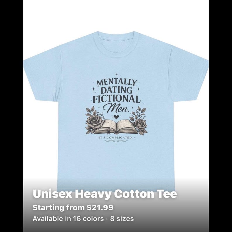 May include: A light blue short-sleeved t-shirt featuring a dark graphic print. The design includes the text "MENTALLY DATING FICTIONAL Men." above an illustration of an open book flanked by two roses, with the text "IT'S COMPLICATED" below the book.