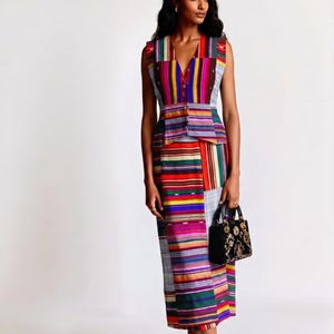 May include: A sleeveless waistcoat and matching midi skirt set featuring a vibrant, multi-coloured horizontal striped pattern in shades of red, yellow, blue, green, and purple. The waistcoat has a V-neckline and button closure, paired with a black handbag.