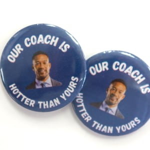 May include: Two circular pin-back buttons with a dark blue background. Each button features a photographic portrait of a man in a suit and tie, surrounded by the white text "OUR COACH IS HOTTER THAN YOURS" arranged in a circular pattern.