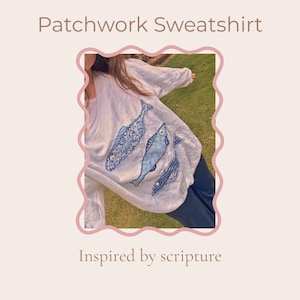 Puede incluir: Una sudadera blanca de manga larga con tres aplicaciones de peces azules de diversos patrones. El texto Patchwork Sweatshirt e Inspired by scripture aparece impreso en la imagen. Los diseños de los peces incluyen texturas florales, lisas y onduladas.