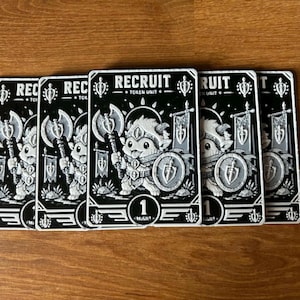 May include: Five rectangular game cards featuring a black and white illustration of a small creature holding an axe and shield. The text RECRUIT TOKEN UNIT is printed at the top, and the number 1 MIGHT is centered at the bottom of each card.