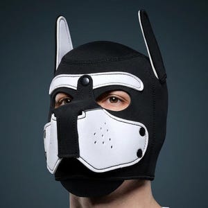 Peut inclure: Un masque de chiot noir et blanc avec un design canin. Le masque a une base noire avec des détails blancs autour des yeux, du nez et des oreilles. Il comprend une sangle avec une fermeture à bouton-pression et de petits trous d'aération.