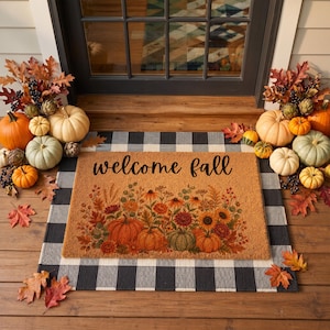 May include: A rectangular coir doormat with the text welcome fall in black script, featuring a printed design of orange pumpkins and autumn flowers. The mat is layered over a black and white buffalo check rug, surrounded by various pumpkins.