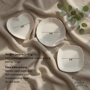 May include: Three off-white ceramic plates in heart, round, and square shapes, each measuring 3.9 inches in width. The set includes text detailing a weight of 140g, vinyl printing, and care instructions including gentle hand wash only.