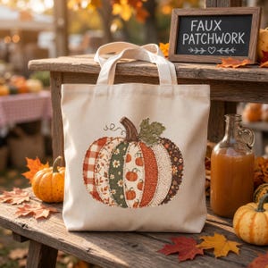 May include: A cream-colored canvas tote bag featuring a central pumpkin graphic composed of various fabric patches in shades of orange, green, and brown. The pumpkin design includes patterns like plaid, floral, and herringbone, with a brown stem and green leaf.