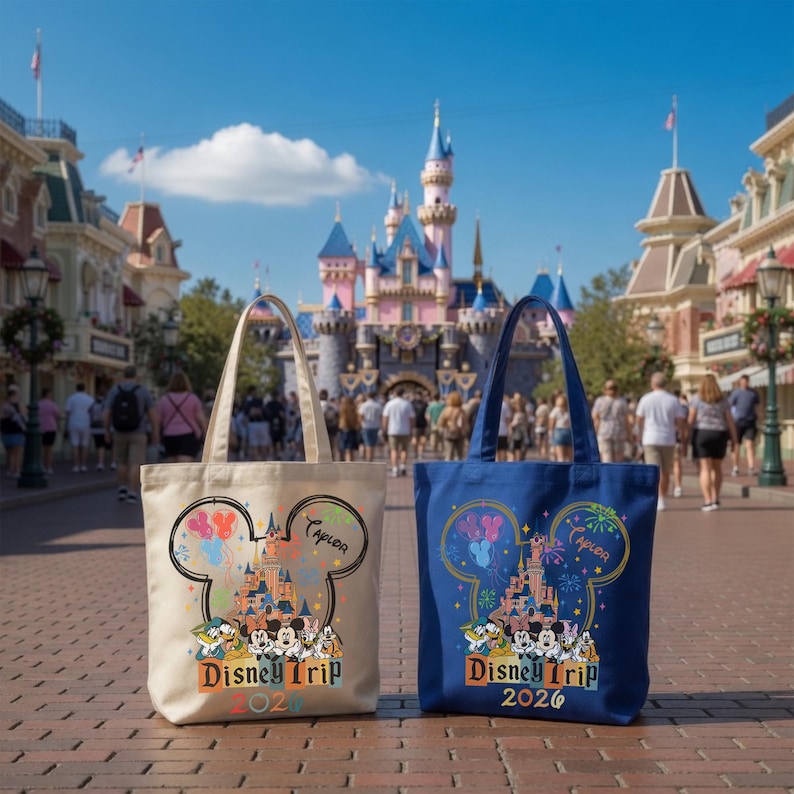Pu&ograve; includere: Due borse in tela, una color crema e una blu, con una grafica di un castello all'interno di una silhouette a orecchie di Topolino, con personaggi, fuochi d'artificio, il nome Taylor e il testo Disney Trip 2026 stampati sul davanti.