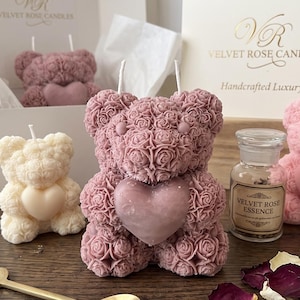 May include: A selection of handcrafted bear-shaped candles in shades of pink and cream, decorated with rose detailing and heart accents. The image includes a gold spoon with lavender, rose petals, and small bottles labelled "Velvet Rose Essence".