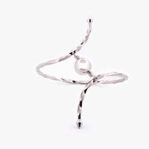 Op de afbeelding: Een zilverkleurige, abstracte armband met een centrale bol en gedraaide, getextureerde banden. De armband heeft een uniek, sculpturaal ontwerp met puntige eindkappen. De algehele esthetiek is modern en minimalistisch.