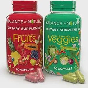 May include: Two supplement bottles, one red and one green, with the text "Balance of Nature" and "Dietary Supplement." The red bottle says "Fruits" and the green bottle says "Veggies." Each bottle contains 90 capsules. Several capsules are scattered in front of the bottles.