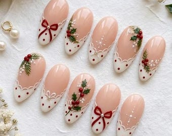 May include: A set of ten almond-shaped press-on nails featuring a nude base with white scalloped tips, red polka dots, and festive holiday accents including painted red bows, green holly leaves, red berries, and delicate white starburst details.