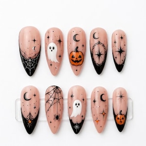 May include: A set of ten almond-shaped press-on nails with a nude base and black tips. The designs feature hand-painted Halloween motifs including white ghosts, orange jack-o'-lanterns, black spiderwebs, spiders, crescent moons, and stars.