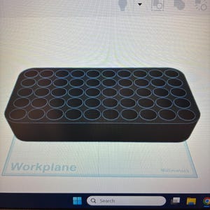 May include: A black rectangular storage block featuring a grid of forty-eight circular holes arranged in six rows and eight columns. The object is displayed on a digital interface labelled Workplane with a grid background and millimetre units.