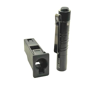 May include: A black Olight flashlight with a metal pocket clip and a textured tail switch, positioned next to a black, rectangular, 3D-printed plastic holster with a hollow center and a square front opening designed for holding the flashlight.