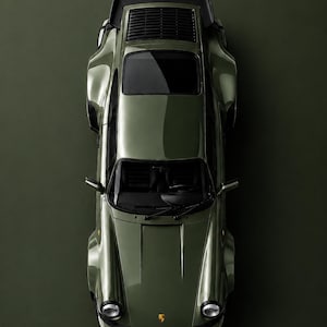 May include: Overhead shot of a green Porsche Turbo sports car. The word "PORSCHE" is at the top, and "TURBO" is at the bottom, with "OAK GREEN METALLIC" below it. The car has a sleek design.