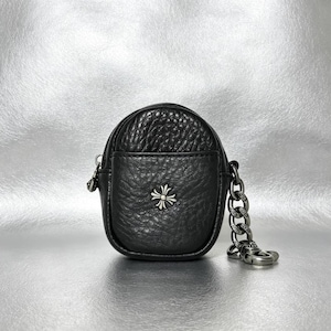 May include: A small black pebbled leather pouch with a rounded shape and a silver-toned metal cross emblem centered on the front. The pouch features a thick silver-toned metal chain link attachment on the side with a matching metal clasp.