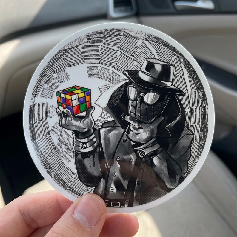 May include: A round sticker featuring a black and white illustration of a character in a trench coat and fedora holding a colorful Rubik's Cube. The background has a textured, swirling design.