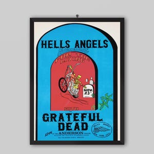 May include: Framed vintage poster with a black border. The poster features the text "HELLS ANGELS" and "GRATEFUL DEAD" in blue and a red archway with a skeleton riding a tricycle. The date "NOV. 23" is also visible.