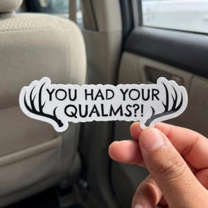 May include: A white die-cut sticker featuring black text that reads "YOU HAD YOUR QUALMS?!" flanked by black silhouettes of deer antlers on both the left and right sides. The sticker has a clean white background and bold black lettering.