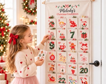 May include: A beige fabric wall-hanging advent calendar with the text Melody's Christmas Countdown. It features twenty-four numbered pockets, each decorated with colorful holiday illustrations including a snowman, gingerbread man, and Santa Claus.