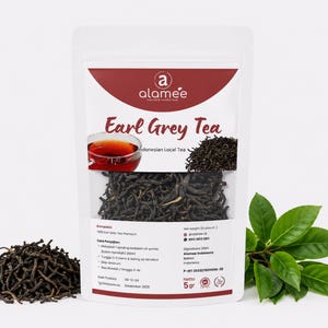 Könnte beinhalten: Ein weißer Beutel mit Earl Grey Tee mit einem roten Banner und dem Markennamen "alamee". Der Beutel enthält lose Teeblätter und trägt den Text "Indonesian Local Tea". Ein kleiner Haufen Teeblätter und grüne Blätter befinden sich neben dem Beutel.