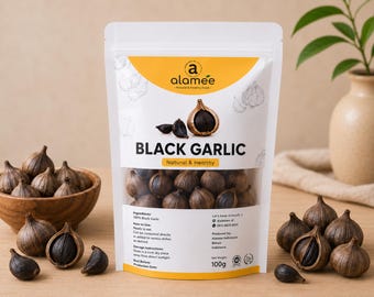 Könnte beinhalten: Ein weißer Standbeutel der Marke Alamee mit schwarzem Knoblauch und gelbem Kopfbereich. Das Etikett zeigt den Text BLACK GARLIC, 100g Nettogewicht und Anwendungshinweise. Der Beutel ist von losen Knoblauchzehen und einer Holzschale umgeben.