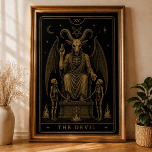 Puede incluir: Impresión enmarcada con marco dorado, que representa una figura con cuernos en un trono, flanqueada por esqueletos y llamas. La obra de arte es en oro y negro, con el texto "THE DEVIL" en la parte inferior. Estilo gótico.