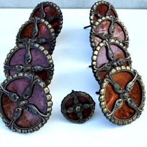 Può includere: Set di pomelli e maniglie decorative per mobili. I pomelli e le maniglie hanno un design circolare con un centro rosso scuro, elementi decorativi in metallo e finitura bronzo. Per mobili o armadi.
