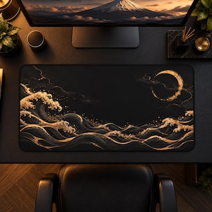 May include: A rectangular desk mat featuring a black background with a gold-toned graphic of stylized ocean waves and a crescent moon. The design includes intricate swirling patterns and fine gold speckles across the dark surface.