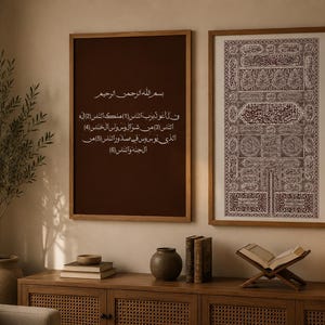 Peut inclure: Deux impressions encadrées d'art islamique sont accrochées au mur. L'une présente du texte arabe sur fond marron foncé, l'autre un motif détaillé. Une lampe, des livres et des objets décoratifs sont sur un meuble en bois.