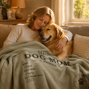 Woman sitting with her Golden Retriever and a personalized Dog Mom blanket in a warm living room.