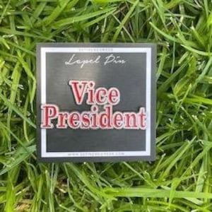 May include: A black and white lapel pin with the text "Vice President" in red letters.