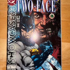 May include: A comic book cover for Showcase '93 featuring Batman and Two-Face. The cover has the text "TWO-FACE" in large white letters. The comic book also features the text "BATMAN DEADSHOT FIRE & ICE". The background is a mix of dark colors.