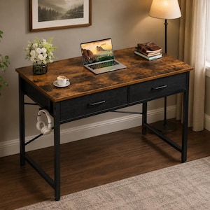 May include: A rustic-style desk with a brown, textured tabletop and black metal frame. It features two black fabric drawers, a laptop, and a pair of headphones. A small coffee cup and a vase of flowers are also on the desk.