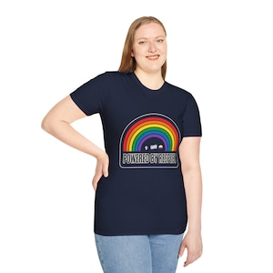 Op de afbeelding: Een marineblauw t-shirt met korte mouwen en een afbeelding van een regenboogboog boven de tekst "POWERED BY RESPECT" in witte hoofdletters. Onder de regenboog staan kleine iconen, waaronder een opgeheven vuist, een transgendervlag en een non-binaire vlag.