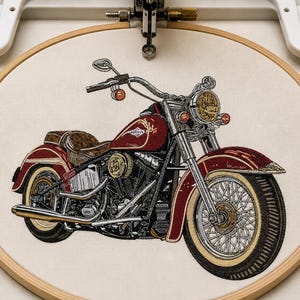 May include: A detailed machine embroidery design of a vintage-style cruiser motorcycle in deep red and black thread, centered within a circular wooden embroidery hoop. The design features wire-spoke wheels, a brown seat, and chrome-colored accents.